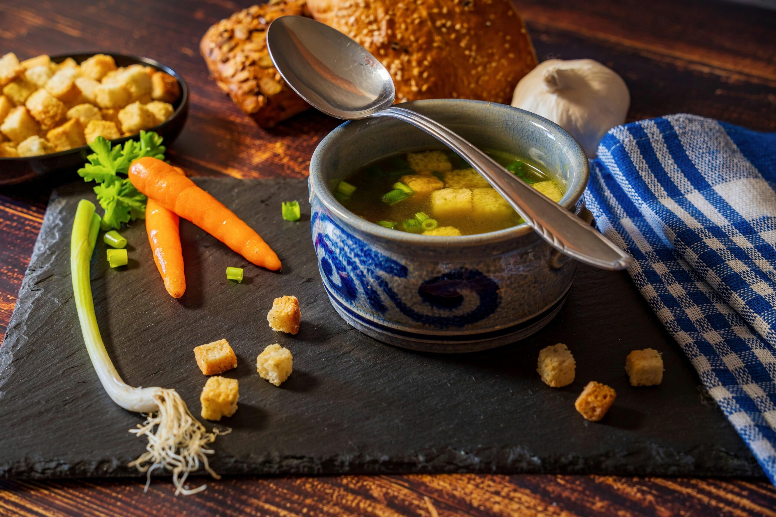 Warm vegetable soup with fresh ingredients and croutons on a rustic table setting.